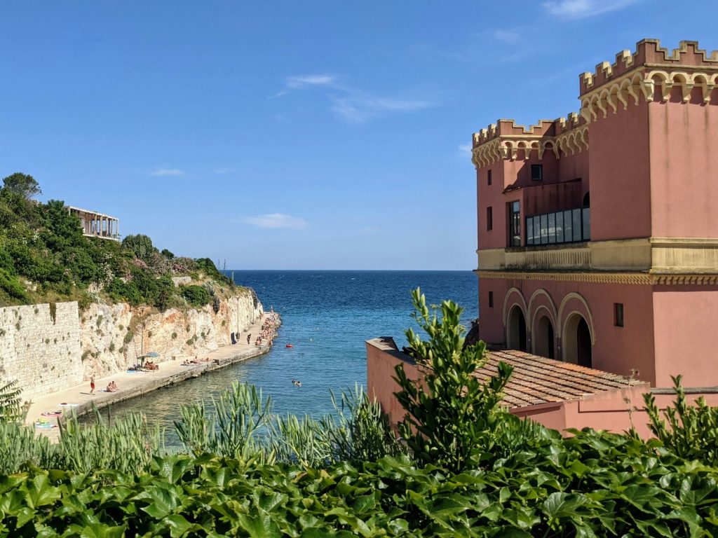 a pink building sitting on top of a cliff next to the ocean