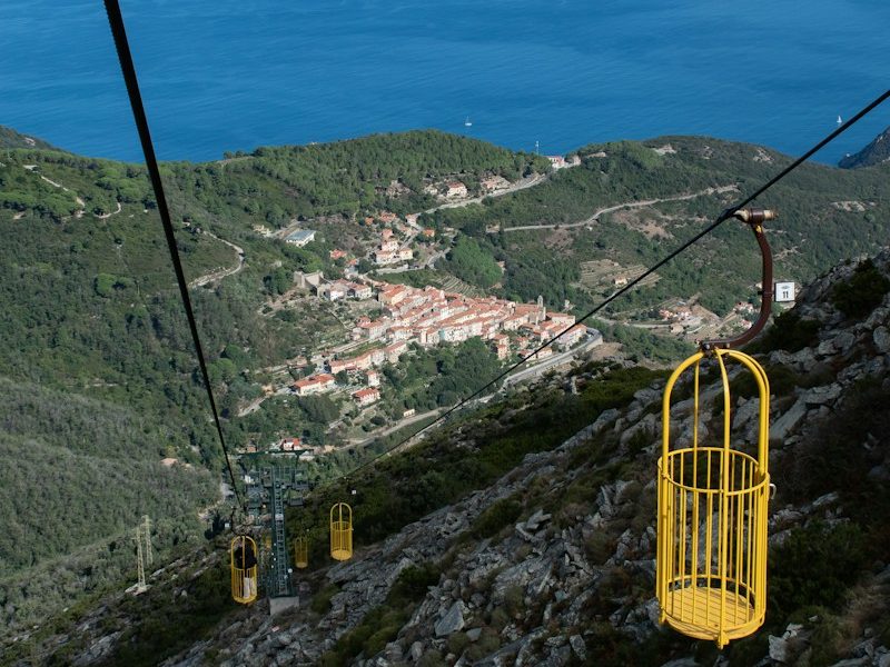 yellow cable car over green trees and mountains during daytime